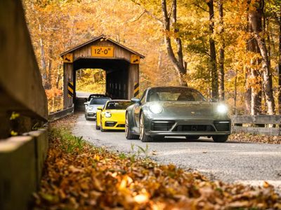 Ferrari 250 GT SWB Berlinetta rijdt op  een weg in een herfstbos